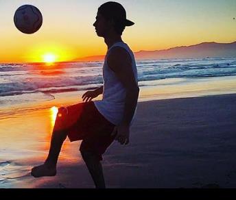 Hunter Sansone dribbling the football in a beach